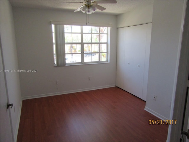 unfurnished bedroom with a textured ceiling, dark hardwood / wood-style floors, a closet, and ceiling fan