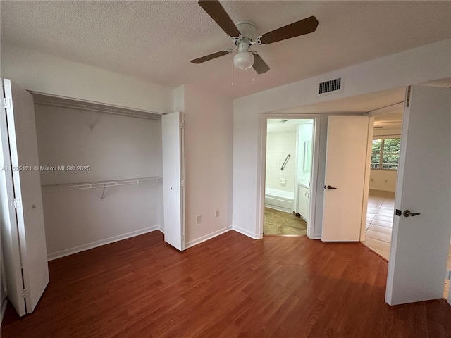 unfurnished bedroom featuring visible vents, a textured ceiling, wood finished floors, a closet, and baseboards