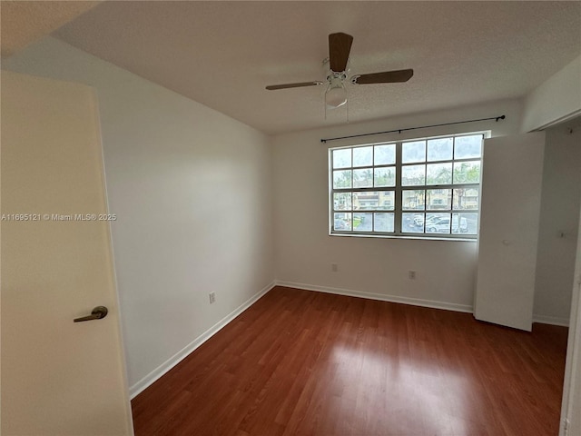 unfurnished bedroom featuring a textured ceiling, a ceiling fan, baseboards, and wood finished floors