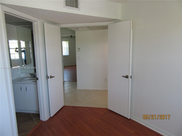 hall with wood-type flooring, a textured ceiling, and sink