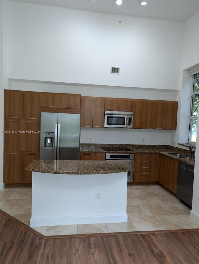 kitchen featuring dark stone countertops, sink, light hardwood / wood-style flooring, and appliances with stainless steel finishes