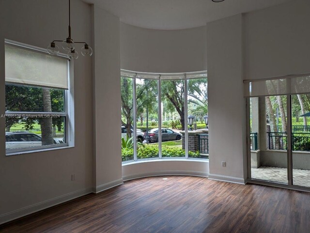 unfurnished room with dark wood-type flooring and a notable chandelier