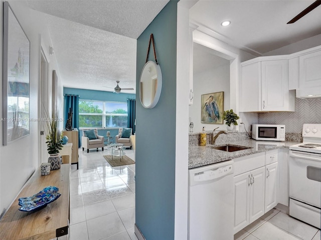 kitchen featuring white appliances, light stone countertops, a textured ceiling, light tile patterned floors, and white cabinetry