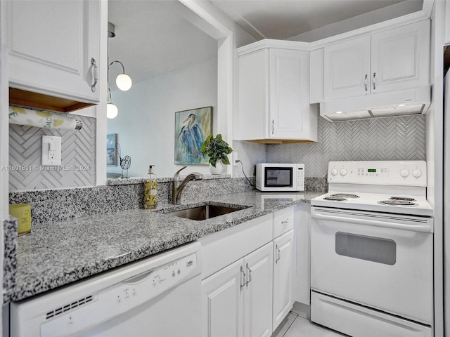 kitchen with light stone countertops, backsplash, white appliances, sink, and white cabinetry