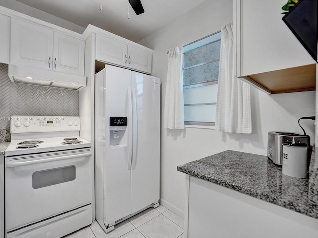 kitchen with tasteful backsplash, dark stone counters, white appliances, light tile patterned floors, and white cabinets