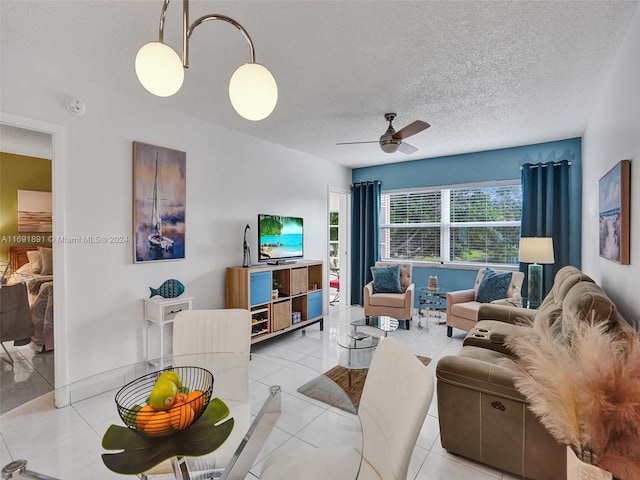 living room featuring ceiling fan, light tile patterned floors, and a textured ceiling