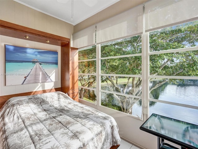 bedroom featuring multiple windows, crown molding, and a water view