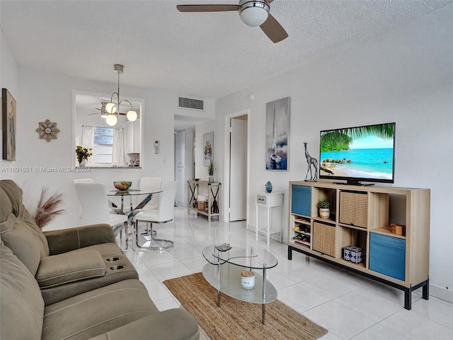 living room featuring light tile patterned floors, a textured ceiling, and ceiling fan