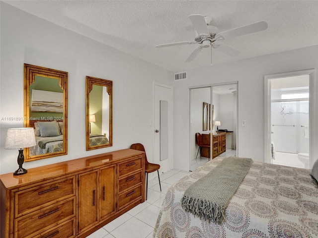 bedroom with ensuite bath, ceiling fan, a textured ceiling, light tile patterned flooring, and a closet