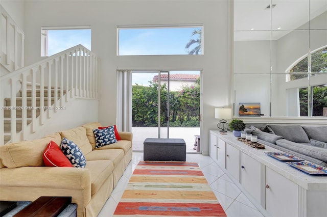 living room with light tile patterned floors, a towering ceiling, and a healthy amount of sunlight