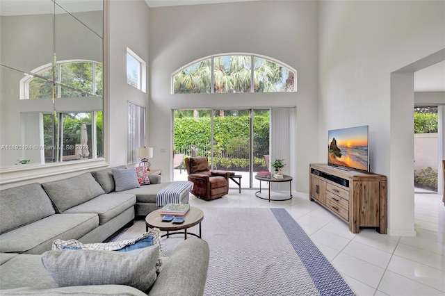 living room with a towering ceiling and light tile patterned flooring