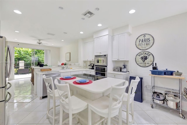 kitchen with ceiling fan, sink, light tile patterned flooring, kitchen peninsula, and white cabinets