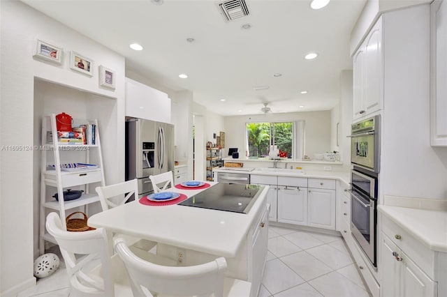 kitchen with white cabinets, sink, light tile patterned floors, appliances with stainless steel finishes, and kitchen peninsula