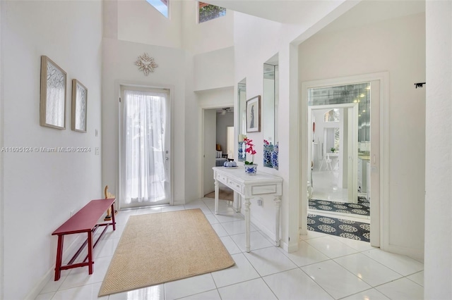 foyer entrance with plenty of natural light, light tile patterned floors, and a towering ceiling