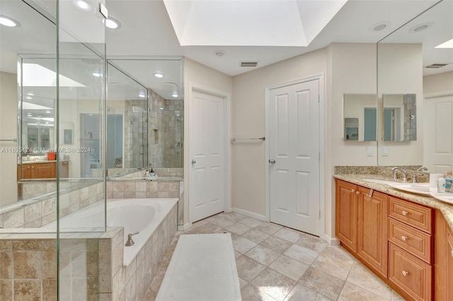 bathroom featuring separate shower and tub, a skylight, and vanity