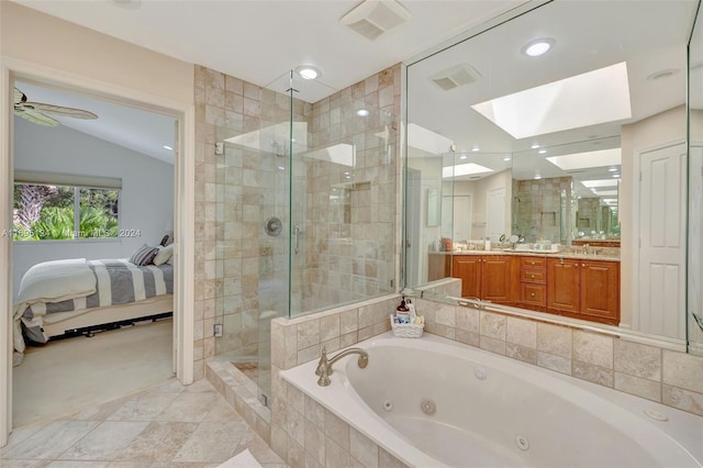 bathroom featuring vanity, plus walk in shower, vaulted ceiling with skylight, ceiling fan, and tile patterned flooring