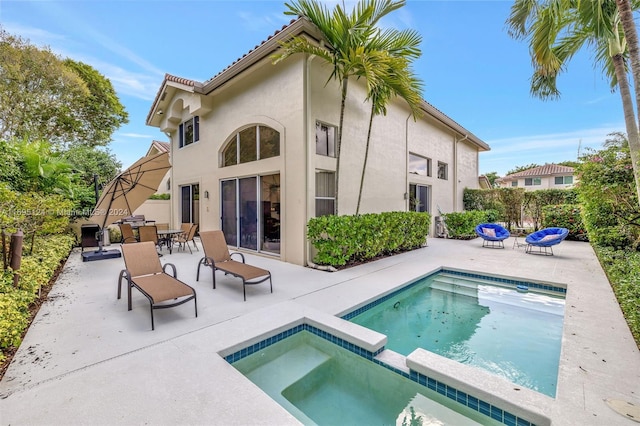 rear view of house with a patio area and a swimming pool with hot tub