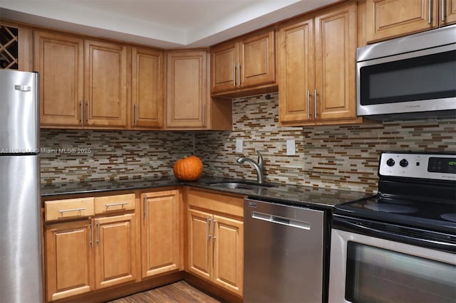 kitchen featuring tasteful backsplash, stainless steel appliances, sink, and dark stone countertops