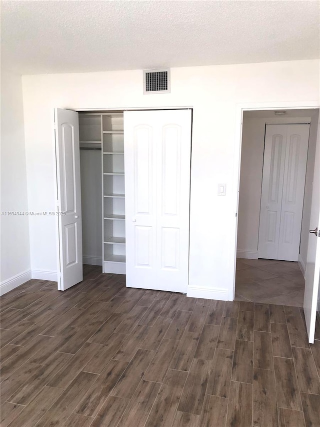 1420 Brickell Bay Dr Unit 1506D, Miami, FL 33131 - unfurnished bedroom featuring dark wood-style floors, a closet, and a textured ceiling