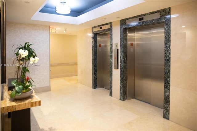 hallway featuring a raised ceiling and elevator