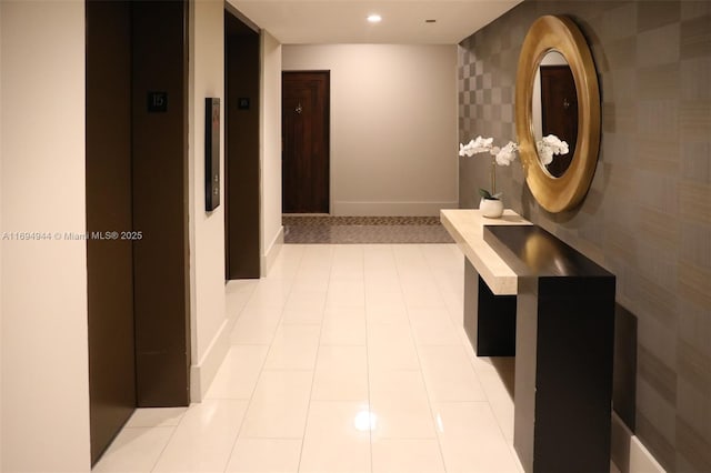 hallway featuring elevator and light tile patterned flooring