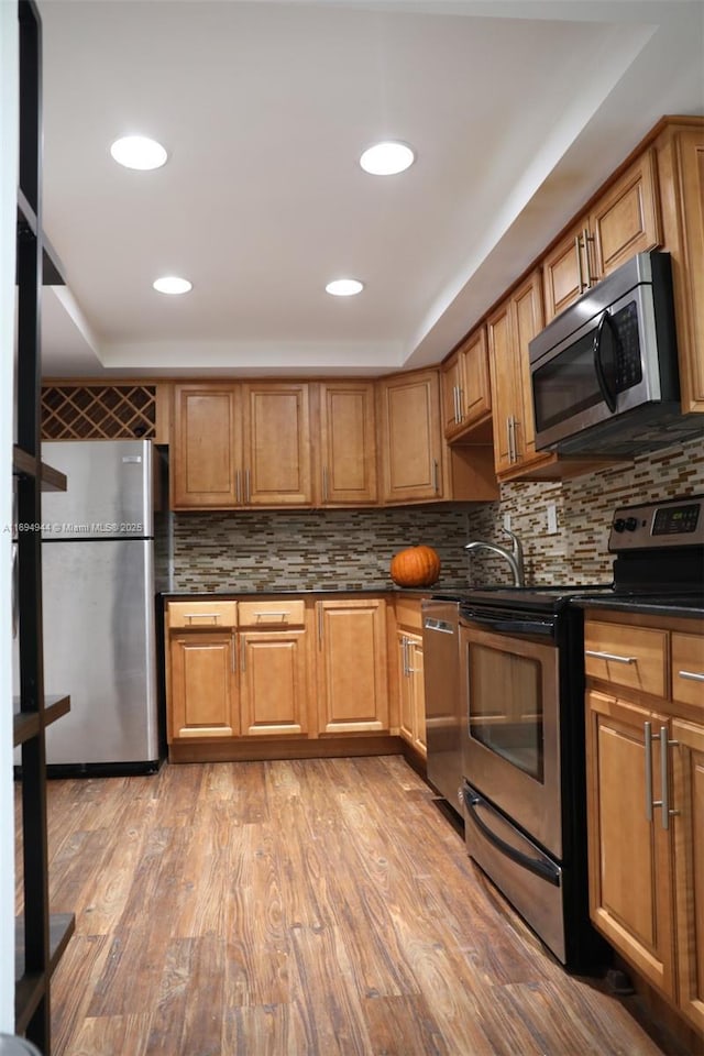 1420 Brickell Bay Dr Unit 1506D, Miami, FL 33131 - kitchen featuring stainless steel appliances, dark countertops, backsplash, light wood finished floors, and brown cabinets