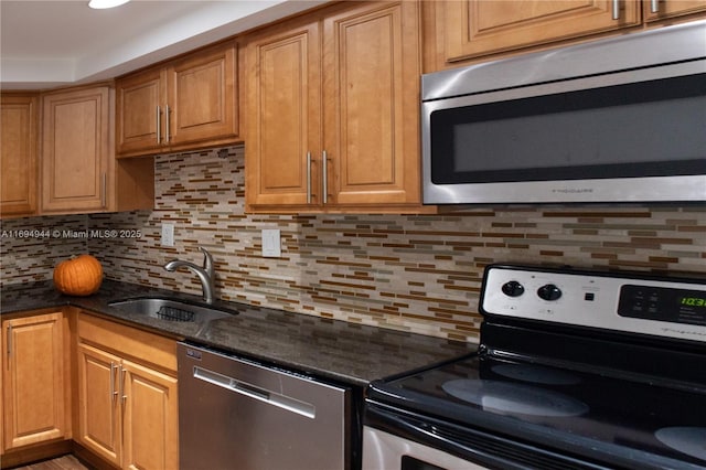 kitchen featuring stainless steel appliances, sink, decorative backsplash, and dark stone counters