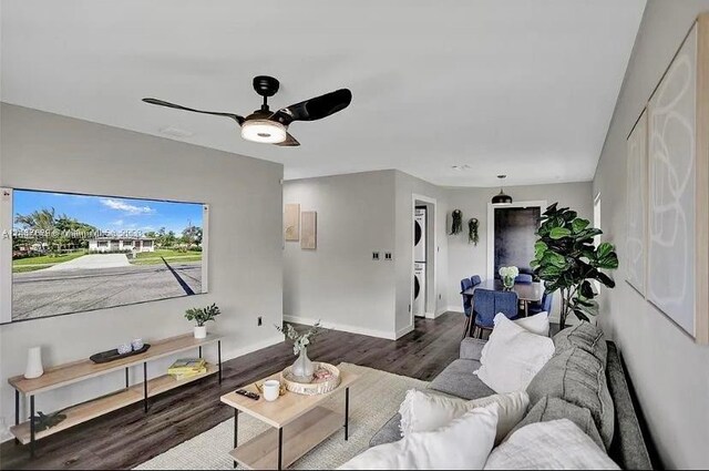 living room featuring hardwood / wood-style flooring, ceiling fan, and stacked washer and dryer