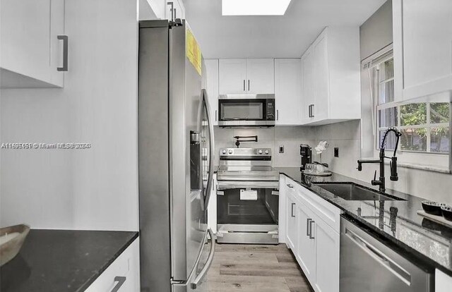 kitchen featuring white cabinets, sink, appliances with stainless steel finishes, and dark stone counters