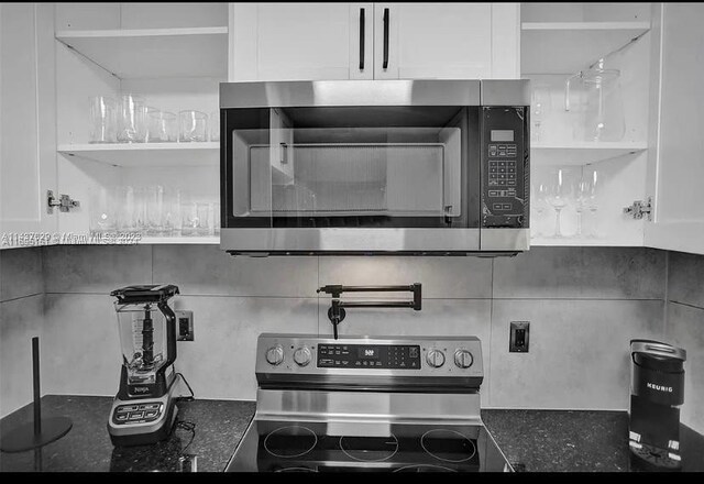 kitchen featuring tasteful backsplash, white cabinets, dark stone counters, and appliances with stainless steel finishes