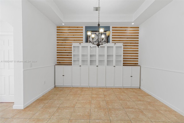 unfurnished dining area with a chandelier, a tray ceiling, and light tile patterned flooring