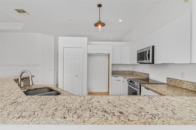 kitchen featuring light stone countertops, stainless steel appliances, sink, decorative light fixtures, and white cabinets