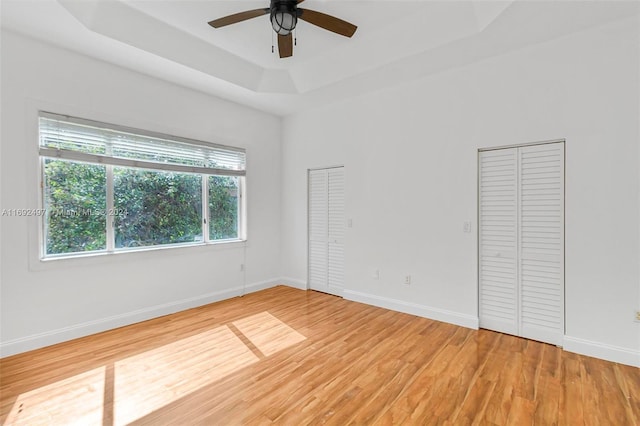 unfurnished room featuring hardwood / wood-style floors, a tray ceiling, and ceiling fan