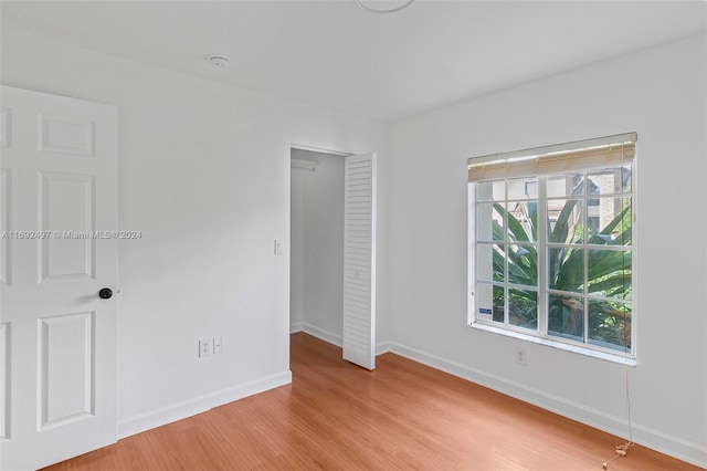 unfurnished bedroom with a closet, light hardwood / wood-style flooring, and multiple windows