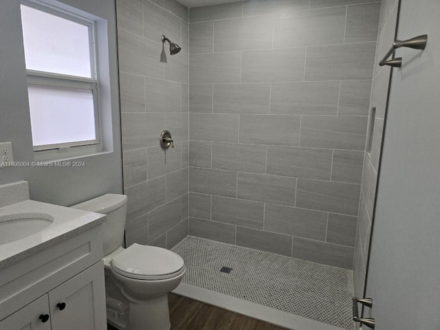 bathroom featuring vanity, toilet, wood-type flooring, and a tile shower