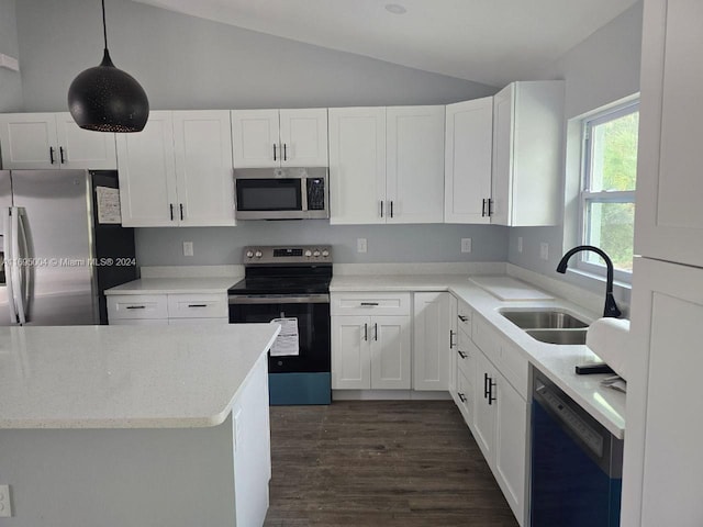 kitchen with appliances with stainless steel finishes, sink, pendant lighting, white cabinetry, and lofted ceiling