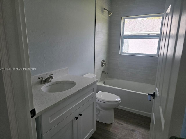 full bathroom with hardwood / wood-style floors, vanity, toilet, and tiled shower / bath