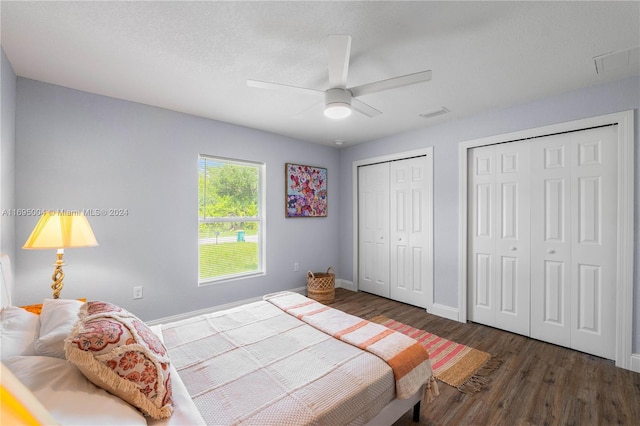 bedroom with multiple closets, ceiling fan, dark wood-type flooring, and a textured ceiling