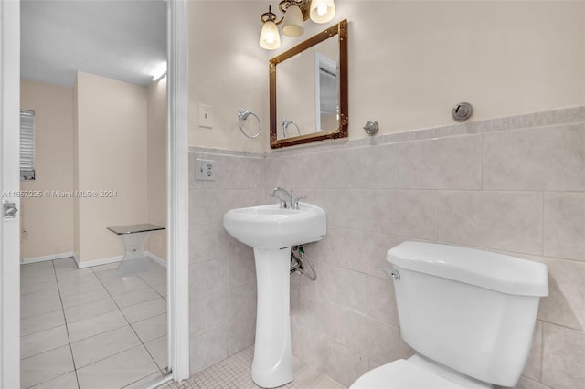 bathroom with toilet, a textured ceiling, tile patterned floors, and tile walls