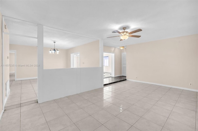 tiled empty room featuring ceiling fan with notable chandelier