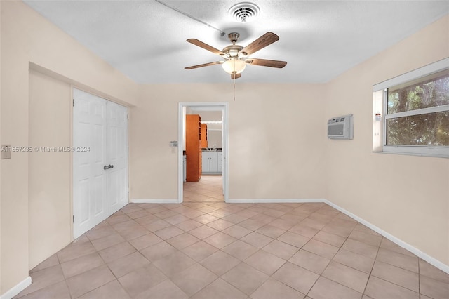 tiled spare room with ceiling fan, a textured ceiling, and a wall unit AC