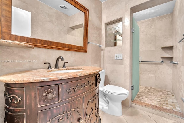 bathroom featuring tile patterned floors, vanity, a shower with shower door, and tile walls