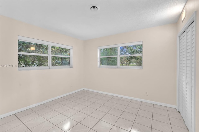 tiled spare room with a textured ceiling