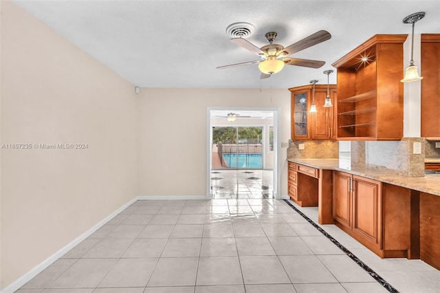 kitchen with backsplash, light stone countertops, hanging light fixtures, and light tile patterned floors