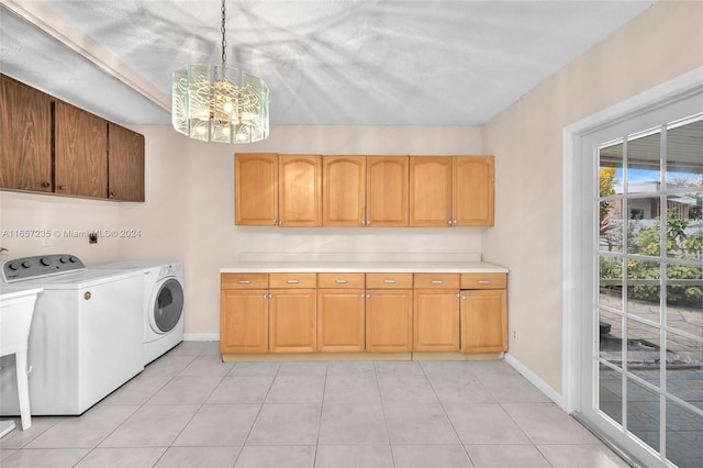 clothes washing area featuring cabinets, light tile patterned floors, a textured ceiling, a notable chandelier, and washing machine and clothes dryer