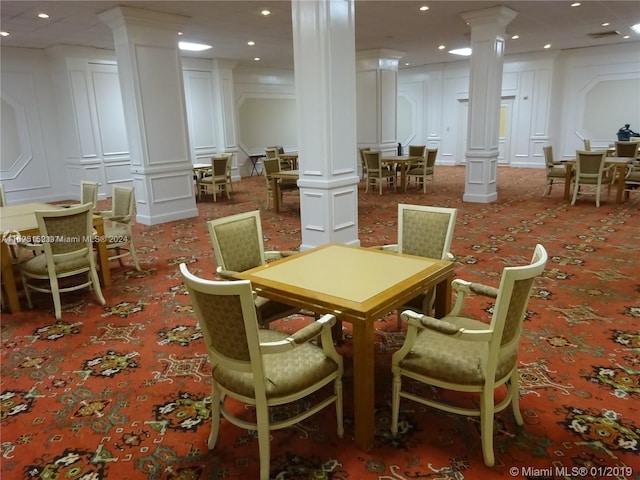 carpeted dining room featuring ornate columns