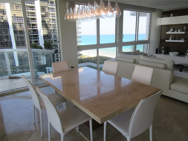 dining area with a water view, a wall of windows, and a notable chandelier