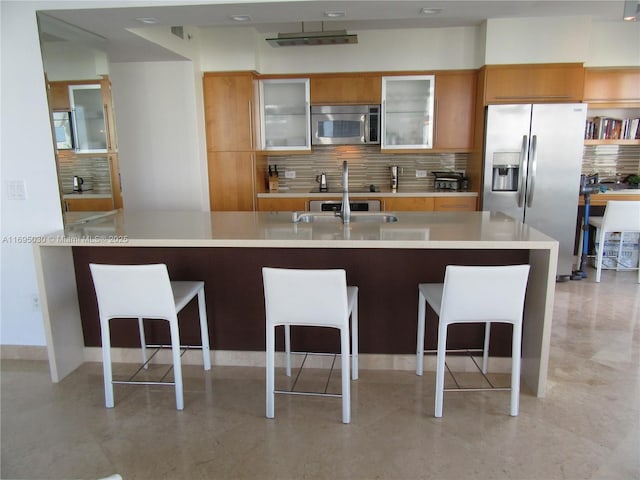 kitchen with backsplash, sink, a kitchen breakfast bar, and appliances with stainless steel finishes