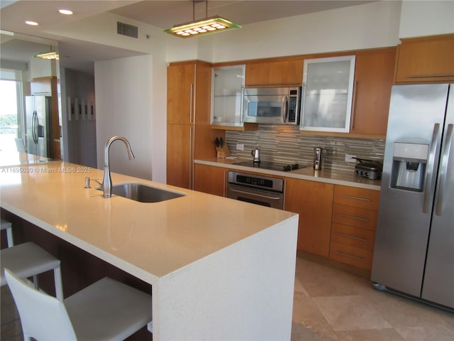 kitchen featuring sink, tasteful backsplash, pendant lighting, a center island with sink, and appliances with stainless steel finishes