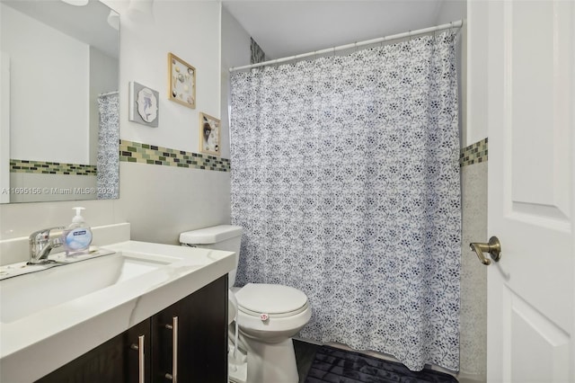 bathroom featuring vanity, toilet, and tile walls